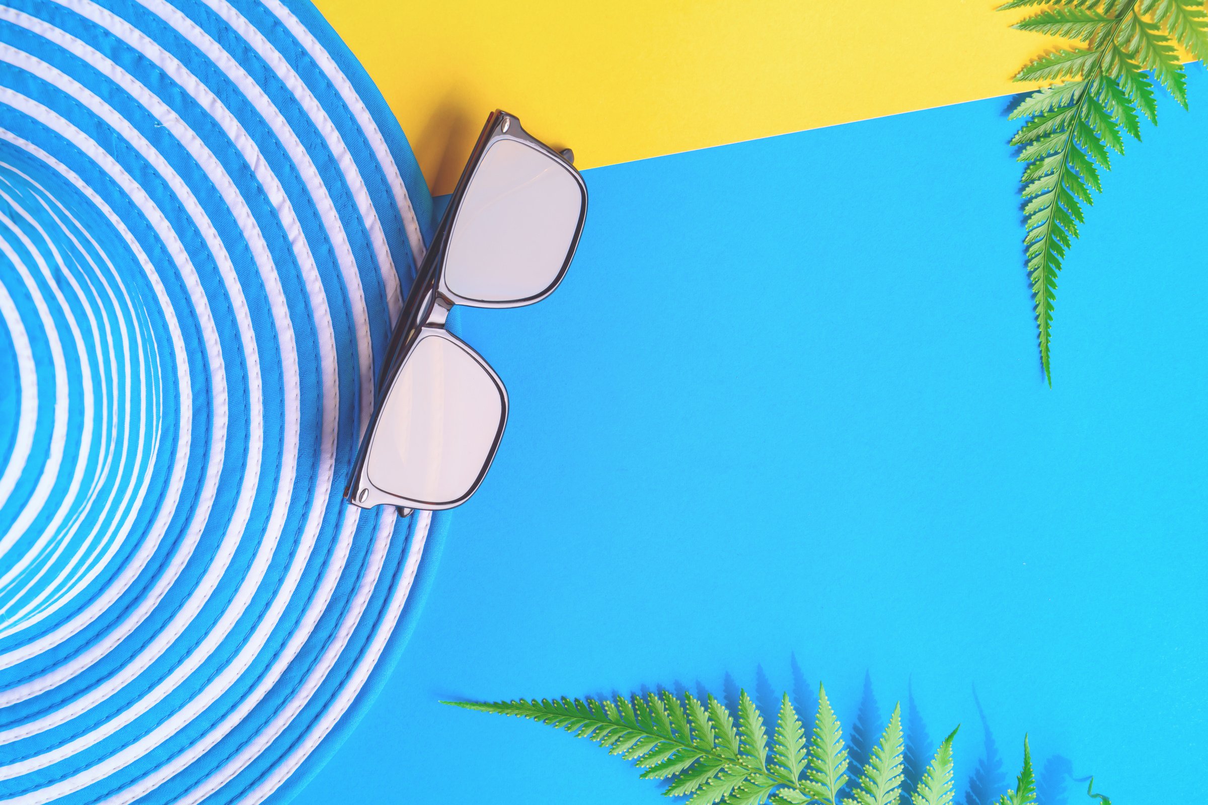 Blue hat and sunglasses on colorful paper